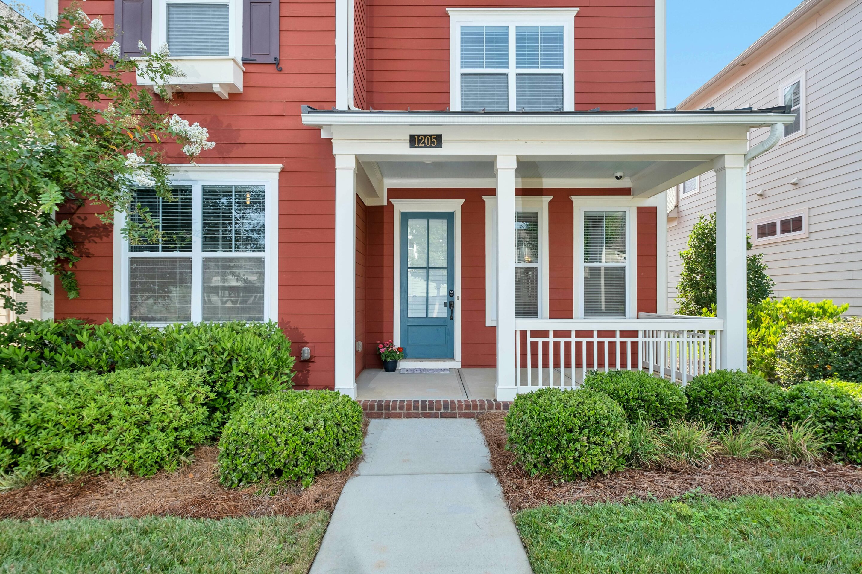 A charming red house with white trim and a welcoming front porch