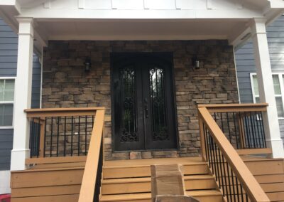 Front-porch-with-a-wooden-railing-and-a-black-welcoming-door